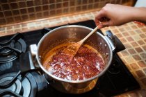 From above of crop anonymous person stirring fig confiture in cooker on stove at home — Stock Photo