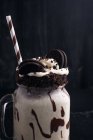 Milkshake saboroso com biscoitos esmagados e palha em vidro com molho de chocolate — Fotografia de Stock