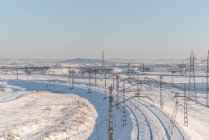 Вид на поезд с беспилотника на железной дороге по заснеженной местности под голубым небом — стоковое фото