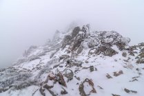 Pendiente de montaña cubierta de nieve y nubes en frío día de invierno en el Parque Nacional Sierra de Guadarrama - foto de stock