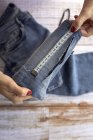 Зверху анонімна жінка-виробник врожаю, використовуючи вимірювальну стрічку, пришиваючи джинси в ательє вдень — стокове фото