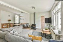 Stilvolles Interieur der modernen Wohnung mit geräumigem Wohnzimmer mit gemütlichem Sofa-Esstisch mit grauen Stühlen — Stockfoto
