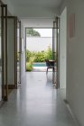 Svuotato ampio corridoio della moderna villa residenziale che conduce al cortile con piscina e piante verdi nella giornata di sole — Foto stock