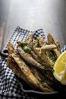 Vista aérea de las apetitosas anchoas fritas con perejil picado y rodaja de limón fresco con carne jugosa - foto de stock