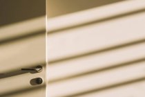 Інтер'єр дверної ручки в порожньому просторому лофт-холі з геометричними тінями і сонячним світлом на білих стінах — стокове фото