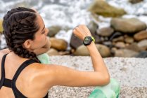 Женщина бегунья проверяет пульс на современном носимом фитнес-браслете во время тренировки в городе — стоковое фото