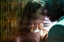 Seitenansicht des Erntepaares mit Glas auf Champagner im Moment des Kusses gegen glänzende Lichtstrahlen, die sich während der Party anschauen — Stockfoto