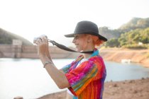 Frau mit schwarzem Hut in einem See beim Fotografieren der Landschaft — Stockfoto