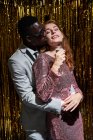 Stylish multiethnic couple with glass of champagne kissing while embracing during New Years Eve celebration — Stock Photo