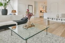 Kreative Gestaltung eines geräumigen Zimmers mit Tischen und Sofa auf Parkett im Haus mit Kronleuchter und Balkon — Stockfoto