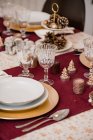 Top view of fork on napkin tied with thread placed near plated and crystal glasses on served table for Christmas dinner — Stock Photo