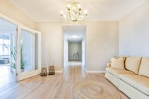 Geräumiges, modernes Wohnzimmer mit bequemem Sofa und Teppich unter Kronleuchter im Tageslicht — Stockfoto