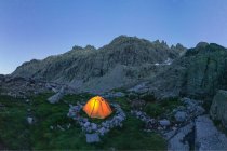Malerischer Blick auf Zelt auf Moos mit Steinen vor schroffem Berg unter blauem Himmel in der Dämmerung — Stockfoto