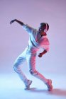Вид збоку на енергійну етнічну жінку в бездротових навушниках і модний одяг, що танцює хіп-хоп з відкритим ротом — стокове фото