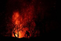 Силуэт фотографа против взрывающейся лавы и магмы, вытекающей из кратера. Извержение вулкана Кумбре-Вьеха на Канарских островах, Испания, 2021 г. — стоковое фото