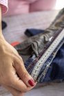 Hohe Schnittwinkel anonyme Schneiderin misst Taille von Jeans auf Holztisch tagsüber — Stockfoto