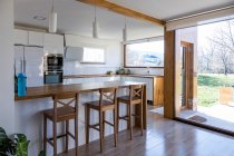 Angolo di cucina elegante con pareti bianche e in mattoni, pavimento in legno, controsoffitti in legno — Foto stock