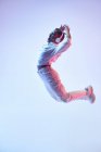 Vista lateral da mulher étnica enérgica em fones de ouvido sem fio e roupas da moda pulando com a boca aberta enquanto dança hip hop — Fotografia de Stock
