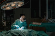 Veterinário em luvas estéreis com pinças cirúrgicas e tesouras operando animal anônimo no hospital — Fotografia de Stock