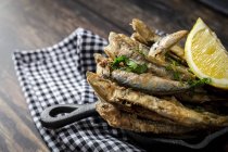 Vista panoramica di appetitose acciughe fritte con prezzemolo tritato e fetta di limone fresco con polpa succosa — Foto stock