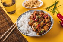 Von oben Komposition Schüssel mit Kung-Pao-Huhn mit weißem Reis Erdnuss und roter Chilischote und grüne Zwiebel und Essstäbchen — Stockfoto
