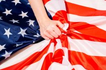 Высокий угол урожая неузнаваемое лицо касается складчатого флага Америки со звездой и полосой орнамента — стоковое фото