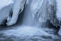 Longue exposition à une chute d'eau rapide traversant un terrain enneigé dans le parc national de la Sierra de Guadarrama — Photo de stock