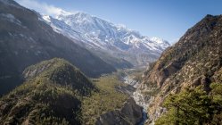 Paisagem pitoresca de rio curvilíneo que flui entre altas montanhas íngremes com picos nevados nas terras altas do Nepal — Fotografia de Stock