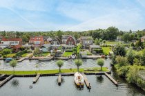 Vue par drone des façades des bâtiments résidentiels entre la rivière et les pelouses avec des arbres sous un ciel nuageux dans la province d'Utrecht Pays-Bas — Photo de stock