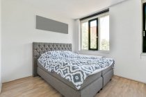 Інтер'єр світлої спальні з великим зручним ліжком зі стильною білизною в денний час — стокове фото