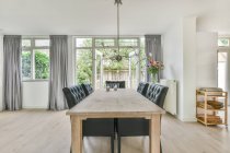 Дерев'яний стіл і чорні шкіряні стільці розміщені в просторій світлій їдальні в сучасному будинку вдень — стокове фото