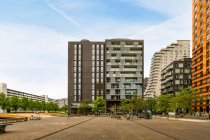 Esterni di edifici moderni contro i marciapiedi con alberi e fiumi sotto il cielo nuvoloso ad Amsterdam Olanda — Foto stock