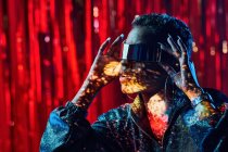 Trendy giovane femmina nera in occhiali cyberpunk con ombre sul viso in fasci di luce in discoteca — Foto stock
