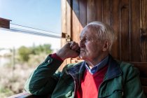 Vista lateral do homem atraente e do homem velho que viaja em uma carruagem de madeira velha do trem que olha para fora da janela — Fotografia de Stock