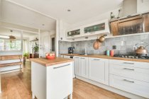 Interior de cozinha espaçosa com aparelhos contemporâneos e móveis brancos em apartamento projetado em estilo mínimo — Fotografia de Stock