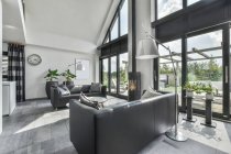 Інтер'єр стильної просторої сіро-кольорової вітальні, обставленої зручними диванами біля скляних дверей — стокове фото