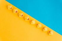 Зверху набір милих гумових іграшок каченят в ряд, розміщених на яскравому синьо-жовтому тлі — стокове фото