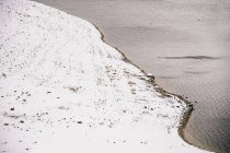 Пейзаж бурлящей реки, протекающей по снежным берегам — стоковое фото