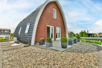 Творчий дизайн арочної будівлі з черепицею даху проти рослин під хмарним небом у провінції Утрехт-Голланд. — стокове фото