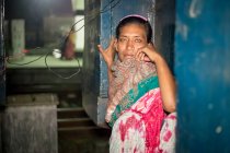 INDIA, BANGLADESH - 2 DE DICIEMBRE DE 2015: Joven india en sari de pie en un edificio de mala calidad mirando a la cámara - foto de stock