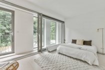 Інтер'єр світлої спальні зі зручним ліжком з різнокольоровими подушками і відкритим вікном в денне світло — стокове фото