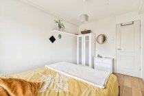 Інтер'єр сучасної спальні з м'яким ліжком і білими стінами в новій квартирі — стокове фото
