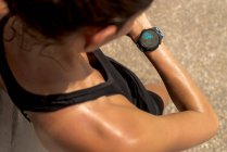 De cima de colheita anônimo suado feminino corredor verificando pulso no rastreador de fitness durante o treino no dia ensolarado no verão — Fotografia de Stock