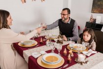 Casal sorridente com copos decorativos de bebida alcoólica acima da mesa servida com velas acesas no dia de Natal em casa — Fotografia de Stock