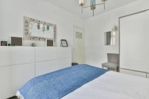 Intérieur de la chambre minimaliste élégante avec lit confortable placé en face armoire blanche avec des éléments décoratifs dans la journée — Photo de stock
