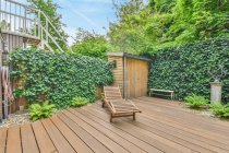 Confortevole sdraio posta sulla terrazza in legno del cottage vicino alla siepe verde in campagna in estate — Foto stock