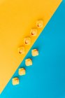 Von oben Set von niedlichen Gummientchen Spielzeug in einer Reihe auf hellblauem und gelbem Hintergrund platziert — Stockfoto