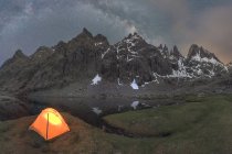 Vue panoramique de la tente sur le bord du lac contre la montagne enneigée sous un ciel nuageux en soirée — Photo de stock