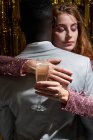 Stylish multiethnic couple with glass of champagne hugging her to an anonymous black guy during New Years Eve celebration — Stock Photo