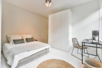 Интерьер просторной спальни с уютной кроватью и большим шкафом в современной новой квартире — стоковое фото